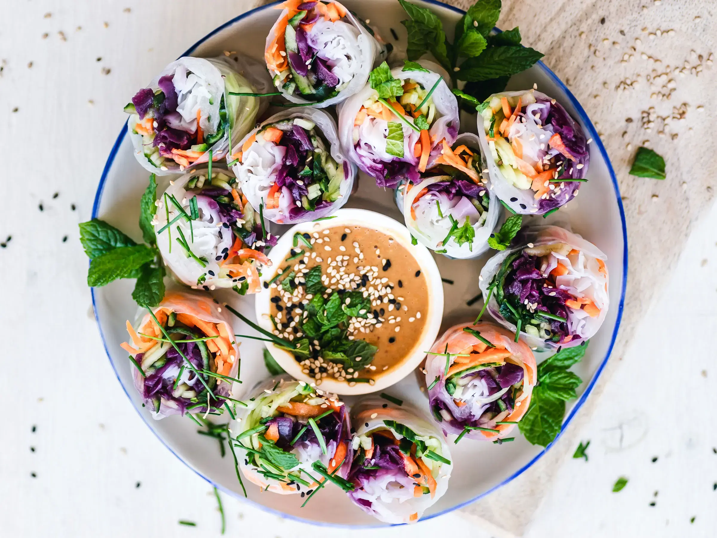 Colorful fresh vegetable spring rolls arranged around a dipping sauce